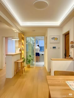 a person standing in the doorway of a kitchen next to a table and stools