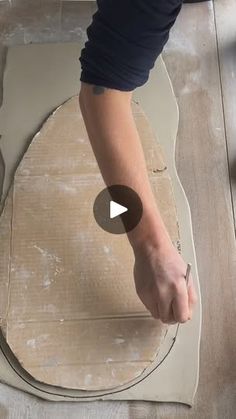 a person is making something out of cardboard on the floor with their hands and thumbnails