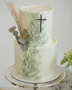 a white cake decorated with silver leaves and a cross