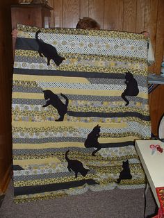 there is a cat quilt on the bed with it's black cats silhouettes