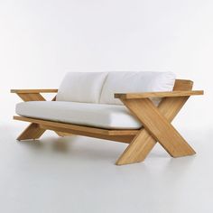 a white couch sitting on top of a wooden frame next to a table with two pillows