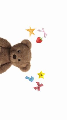 a brown teddy bear laying on top of a white surface with stars and confetti