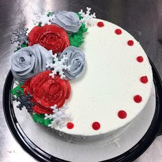 a white cake with red and grey frosting roses