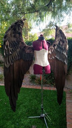 a mannequin with wings on top of it in the grass next to a tree