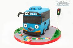 a blue bus cake sitting on top of a table next to a green traffic light