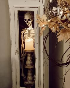 a skeleton sitting in a cabinet with a lit candle on it's side,