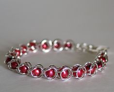 a silver bracelet with red beads on it