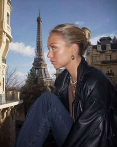 a woman sitting in front of the eiffel tower with her hair pulled back