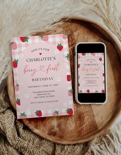 a cell phone sitting next to a pink and white birthday card on top of a wooden plate