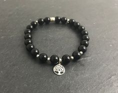 This bracelet of black onyx beads with sterling silver accents, It features a sterling silver Tree of Life charm.  All strung on an elasticated cord that will fit comfortably on your wrist. DETAILS (10mm) Black onyx absorbs and transforms negative energy. It is a stone of happiness, good fortune and strength.  The Tree of Life symbol crosses many cultures and, in general, means rebirth, knowledge or wisdom. All Orinoco Moon Products have a brand tag.  This sterling silver tag has been hand engra Black Spiritual Bracelets With Silver Beads, Spiritual Black Bracelets With Silver Beads, Poison Tree, Beaded Bracelet For Men, Tree Of Life Symbol, Tree Of, Tree Of Life Bracelet, Life Symbol, Silver Tree