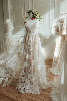 wedding gowns are on display in a room with white walls and wooden flooring