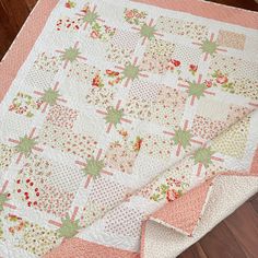 a pink and white quilt on top of a wooden floor