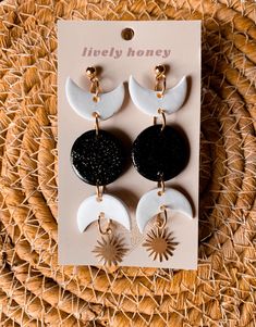 three pairs of earrings with black and white moon charms on top of a wicker basket