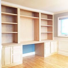 an empty room with wooden flooring and built in cabinets on either side of the window