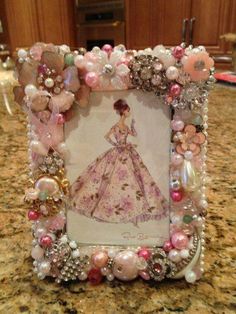 a pink and white dress with pearls on it is sitting in front of a counter top