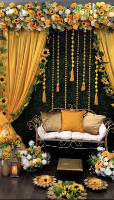 a couch sitting under a yellow drape covered with flowers and tassels on top of it