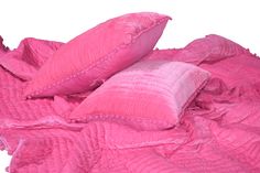 two pink pillows are laying on top of a pink comforter that has ruffled edges