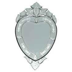 a heart shaped mirror hanging on the wall in front of a white background with an ornate design