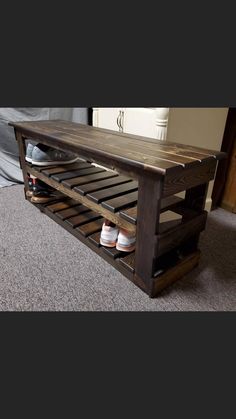 a wooden bench with shoes underneath it on carpeted floor next to wall and door