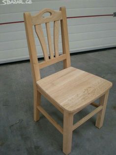 a wooden chair sitting on top of a cement floor next to a white garage door