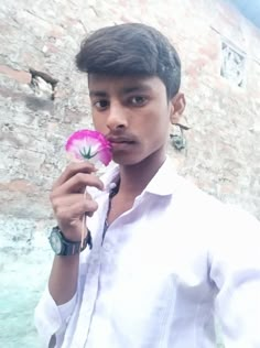 a young man holding a pink flower in his hand