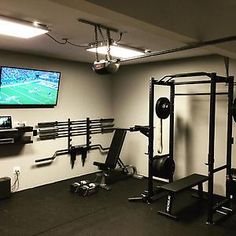 a home gym with equipment and a flat screen tv mounted on the wall above it