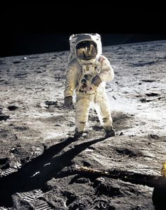 an astronaut standing on the moon holding a baseball bat and looking at something in his hand