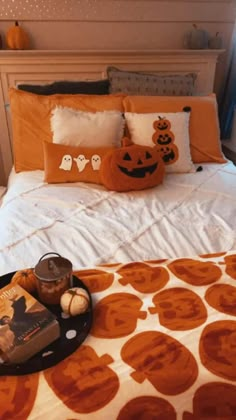 a bed with an orange and white bedspread, two pumpkins on the pillow