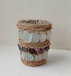 a close up of a glass vase on a white surface with rope wrapped around it