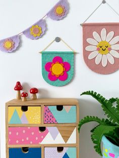 a wooden dresser sitting next to a plant and wall hangings