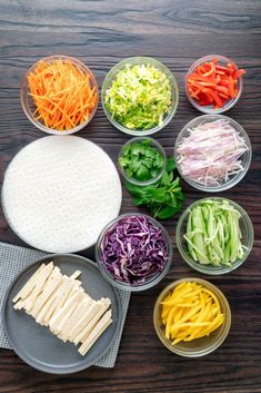 several bowls with different types of vegetables in them on a wooden table, including carrots, celery, cabbage, and noodles