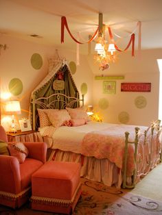 a bedroom decorated in pink and green with polka dots on the walls, bedding, chair, and chandelier