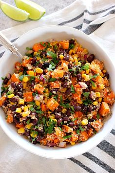 a white bowl filled with black beans, corn and cilantro next to a lime wedge