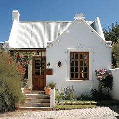 a small white house with two doors and steps leading up to the front door area