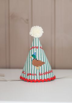 a small green and white striped party hat with a pom - pom on top