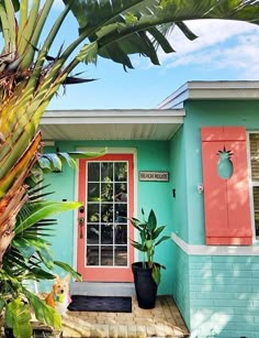 a blue house with red shutters and palm trees