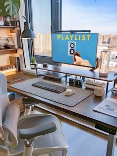 a desk with a monitor, keyboard and mouse on it in front of a window