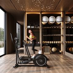 a woman is running on a treadmill in a room with large windows and shelves