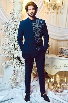 a man in a tuxedo standing next to a table