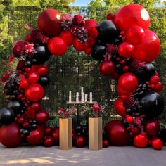 a large red and black balloon arch is set up for an outdoor event with candles