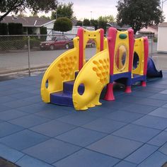 children's playground equipment on the sidewalk in front of a fenced off area