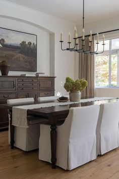 a dining room table with white chairs and a chandelier