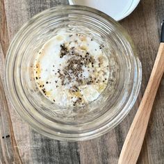 a glass bowl filled with oatmeal next to two wooden spoons on top of a table