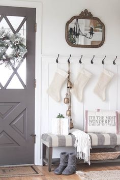 the entryway is decorated for christmas with stockings hanging from hooks and boots on the bench