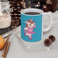 a coffee mug with an image of a unicorn on it next to pine cones and candles