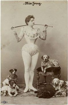 an old photo of a woman with four dogs in front of her and holding a stick