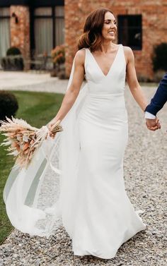 a bride and groom holding hands in front of a brick building