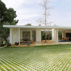 a white house sitting in the middle of a lush green field next to a swimming pool