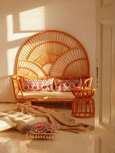 a living room with a rattan couch and pillows on the floor next to it