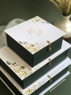 three boxes stacked on top of each other with flowers and leaves painted on the sides